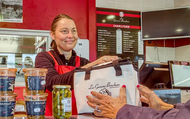 Bouchère remettant un colis de viande à une cliente à Saint-Cast-le-Guildo